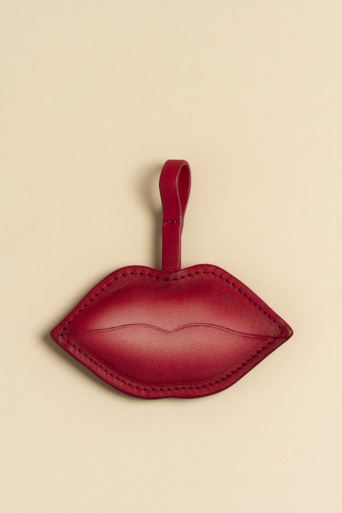 Charm Beso de cuero Arthelier sobre fondo crema