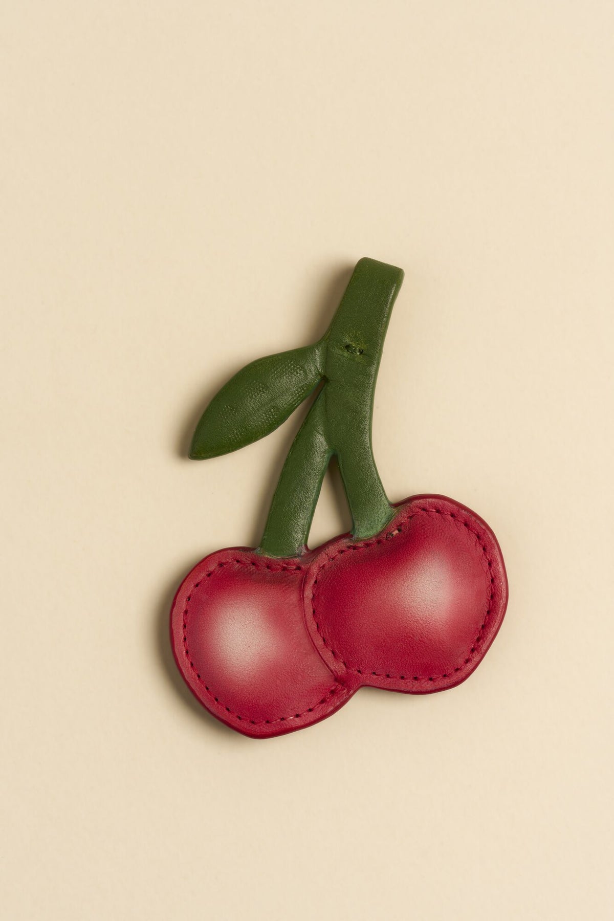 Charm Cereza de cuero Arthelier sobre fondo crema