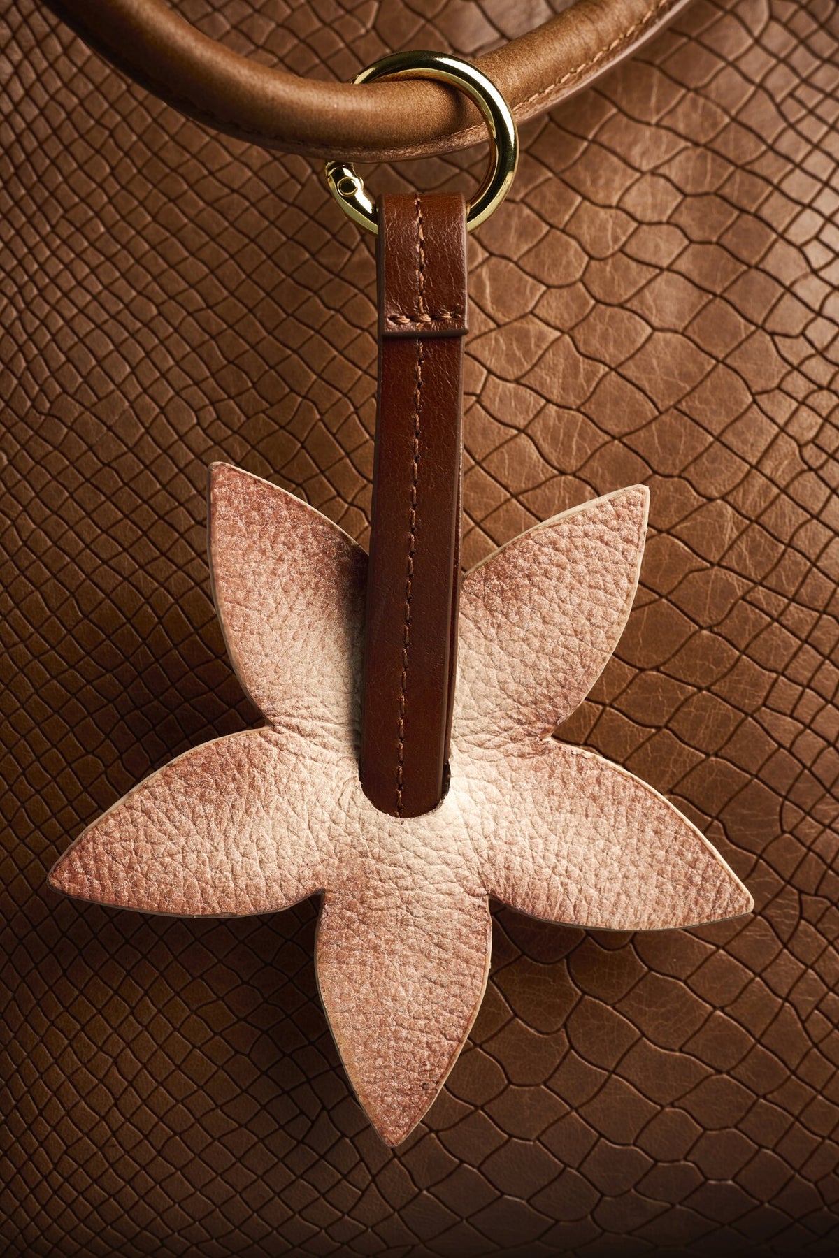 Charm Flor de cuero Arthelier colgado en un bolso