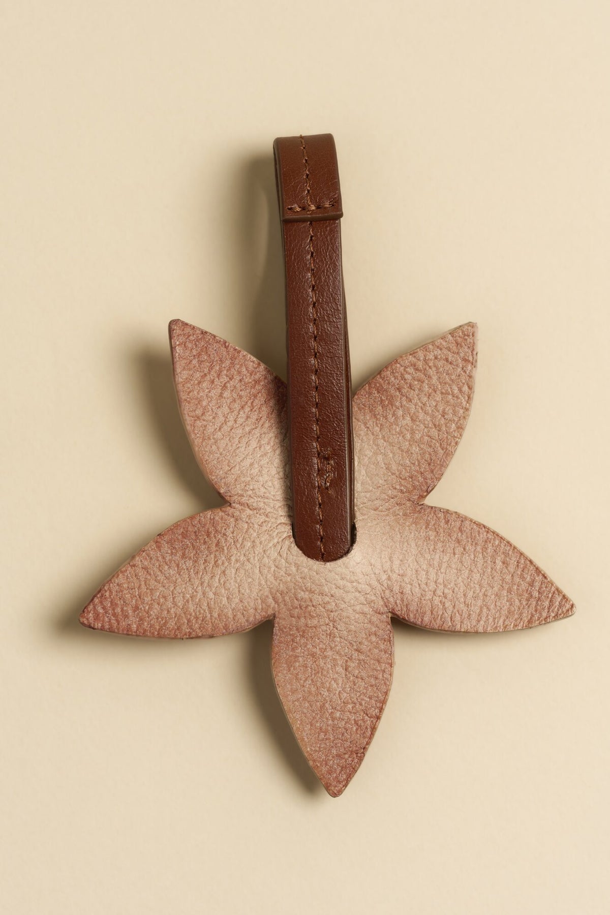 Charm Flor de cuero Arthelier sobre fondo crema